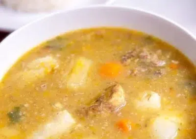 Bol de soupe avec légumes et viande, plat de riz en arrière-plan
